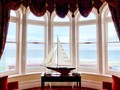 a-model-boat-in-a-bay-window-looking-out-to-sea-B8446N3